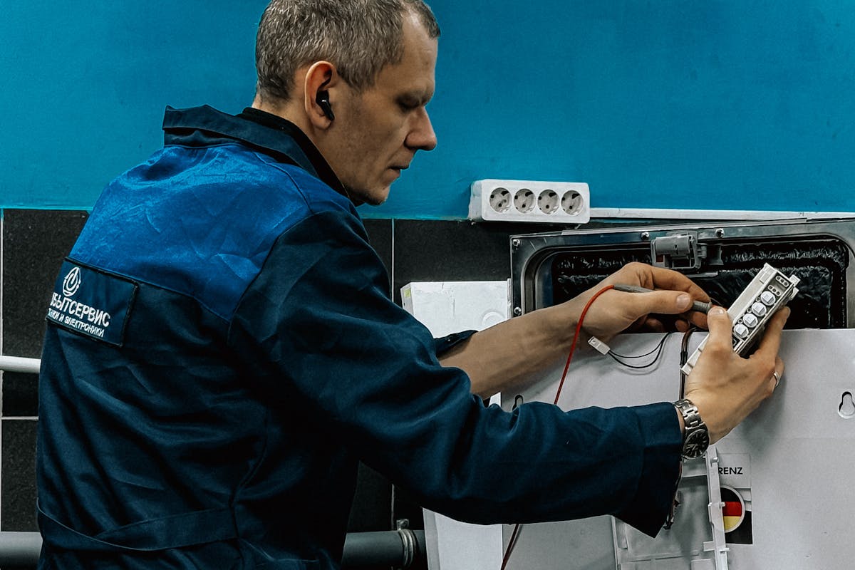 Professional technician in blue uniform repairing a washing machine at a home in Bengaluru